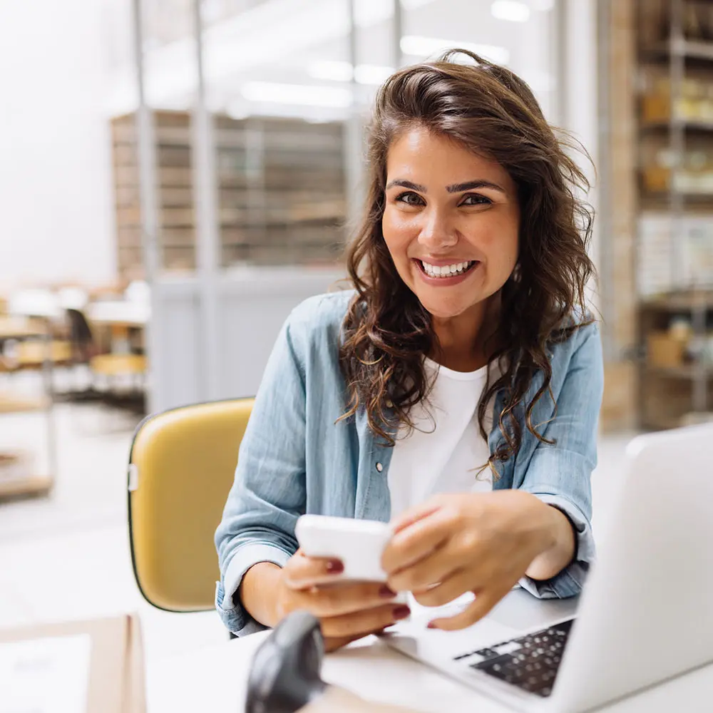 young business owner looking at the camera with a phone in her hand